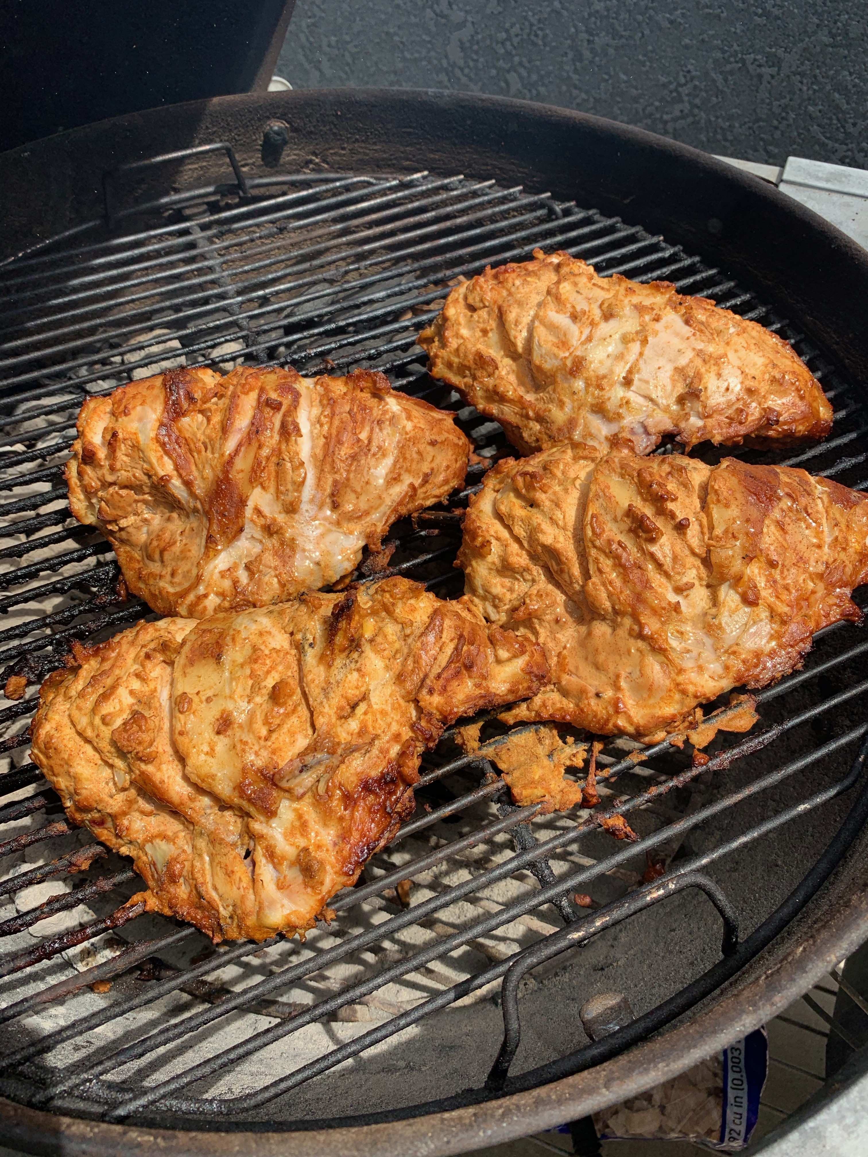 Marinated chicken pieces grilling over charcoal